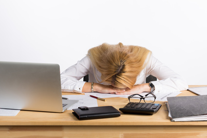 Tired businesswoman sleeping on the desk. Read these tips to sleep better.