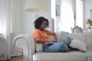 Smiling lady sitting on the couch with her laptop. Maintaining your mental health while working from home